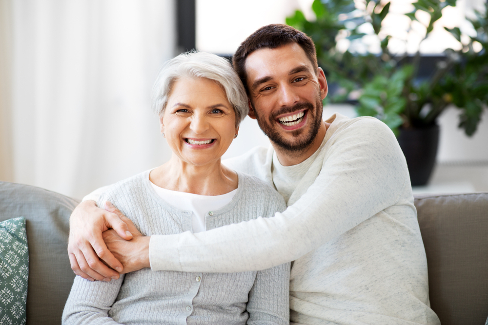 happy smiling senior mother with adult son hugging at home