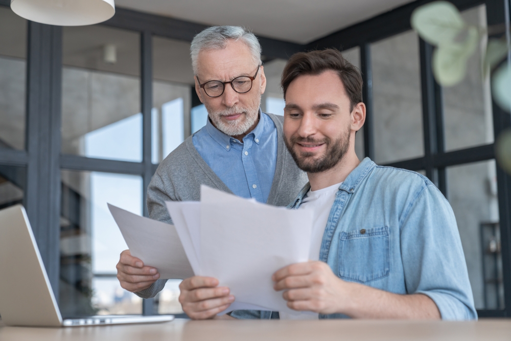 Caring loving adult son helping his old senior elderly father paying bills