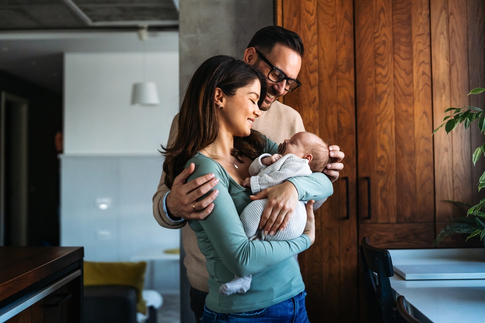 Happy young mother, father with new born baby at home
