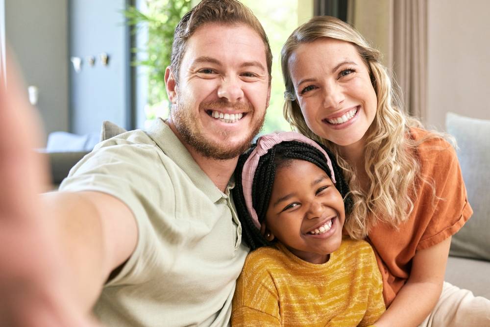 Happy family, adoption and smile for selfie love, relax or bonding in happiness together at home