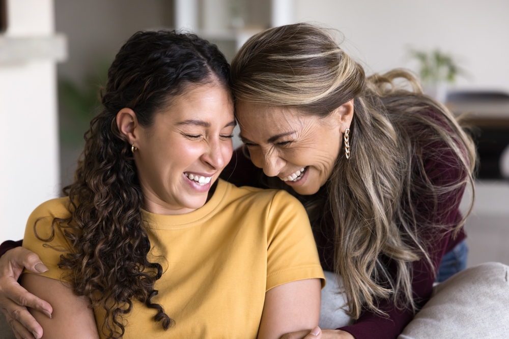 happy loving single mother hug shoulders of smiling adolescent daughter